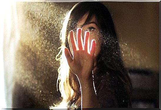 Woman putting her hand in beam of light.