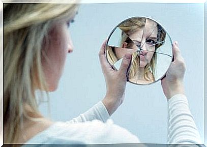 woman looking at herself in broken mirror