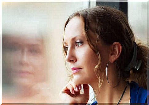 thoughtful woman leaning against window